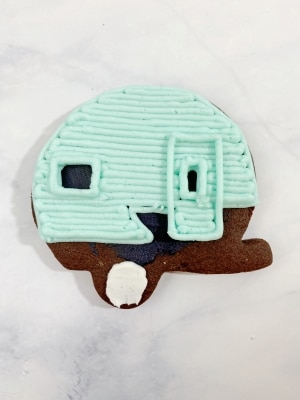 Outline the window and door window with the same teal frosting/tip size. Then, outline the entire door shape. 