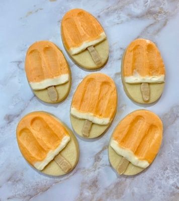 orange flavored buttercream on creamsicle decorated sugar cookies