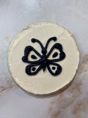 black buttercream butterfly on white buttercream cookie