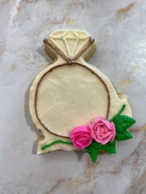 piping a vine onto the floral engagement ring cookies
