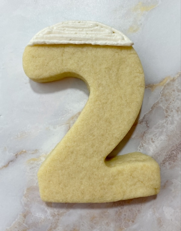 white buttercream on two shaped cookie