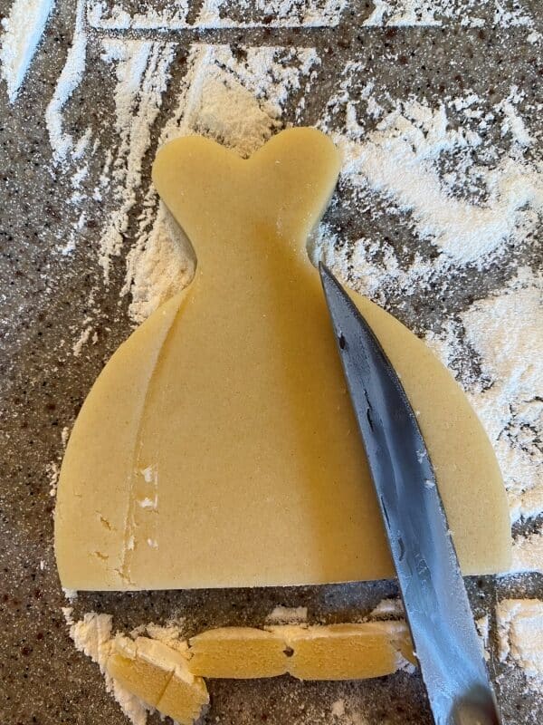using a knife to outline on the cookie where to outline the new edges of the cookie cutter