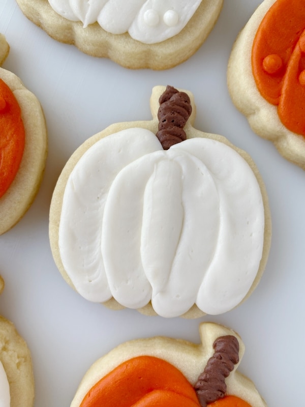 white decorated pumpkin cookies with buttercream
